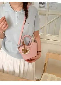 Detail of pink mini bucket bag featuring a wooden horse charm and fine leather texture