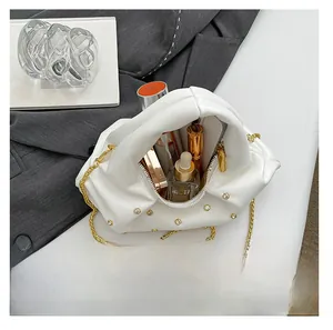 Internal view of a white pleated rivet bag showing storage for cosmetics and a gold chain
