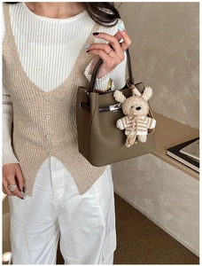 Detail of coffee brown lychee leather bucket bag with metal buckle and cute bear charm