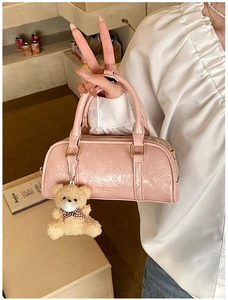 Pink boston bag with ruched texture, gold hardware, and a cute plush bear charm detail