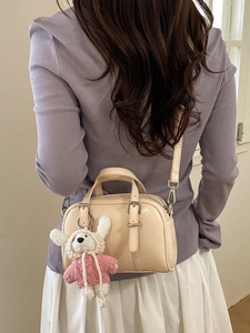 Minimalist beige crossbody bag with cute teddy bear charm on model back view