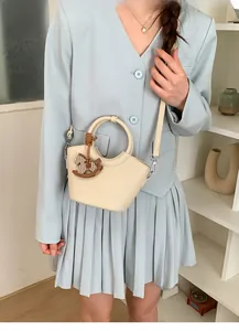 Minimalistische beige Beuteltasche mit Metallgriff und Pony-Anhänger in gemütlicher Szene