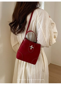 Detail of red faux suede bucket bag with silver cross lock and detachable shoulder strap