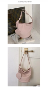 Pink bucket bag with lychee texture featuring a round charm and stylish knotted strap