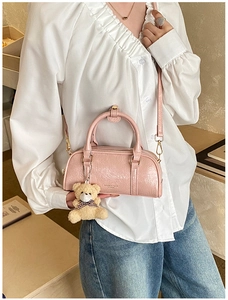 Pink patent leather Boston bag styled with plush bear charm and skinny strap