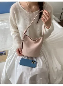 Detail of light pink bucket bag showing lychee grain texture and knotted shoulder strap