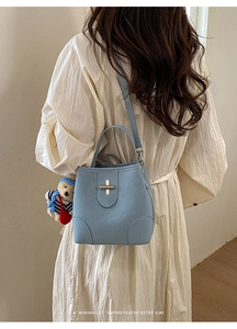 Detail of light blue bucket bag showing silver clasp and cute bear pendant accessory