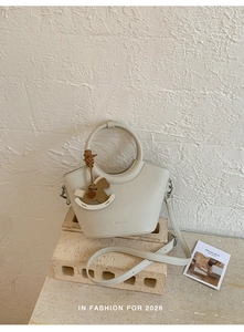 Detail of cream lychee leather bucket bag with ring handle and rocking horse charm