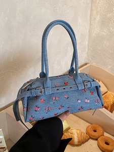 Floral denim bowling bag with red rose pattern and vintage buckle straps in a lifestyle view