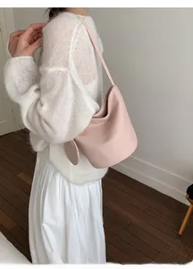 Side view of light pink leather bucket bag with matching coin purse on a model