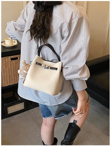 Detail of cream leather bucket bag with silver twist lock and bear charm