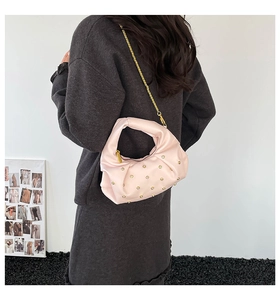 Detailed view of light pink pleated handbag with gold studs and a fine chain strap