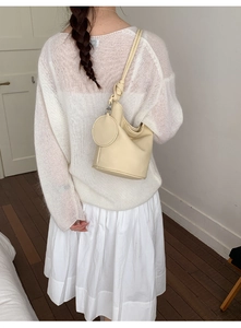 Detail of beige leather bucket bag with knot shoulder strap and round coin purse accessory