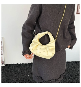 Detail of cream pleated cloud bag with rhinestones and gold chain strap on model