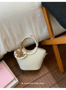 Detail of white lychee leather bucket bag with round handle and wooden horse charm