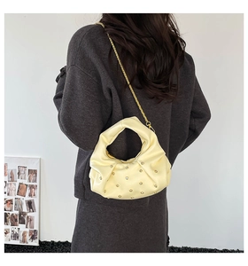 Detail of a creamy yellow pleated cloud bag with sparkling rhinestones and gold chain strap