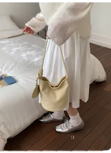 Detail of beige bucket bag with lychee pattern leather and matching round charm pendant
