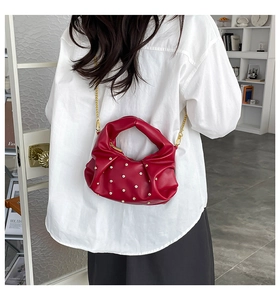 Detail of red pleated leather bag with white pearls and gold chain strap