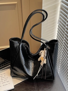 Glossy black leather tote bag with a beige dog charm and wrinkled texture for daily commute