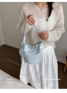 Detail of light blue bucket bag with leather texture and stylish knot on the shoulder strap