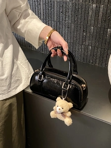 Classic black patent leather bowling handbag with gold zipper and bear plush pendant