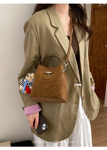 Brown suede crossbody bag with metal lock and cute bear charm shown on model