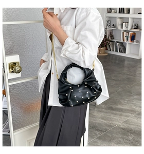 Detail of black pleated cloud bag featuring gold stud accents and elegant chain strap
