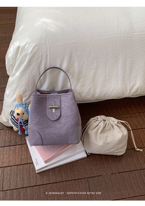 Detail of purple bucket bag with silver turn-lock and beige checkered drawstring pouch