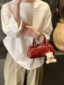 Deep red glossy Boston handbag with gold hardware and a cute plush bear charm