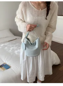 Close-up of light blue bucket bag showing knot detail and leather round charm
