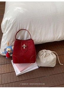 Detail of red leather bucket bag with silver twist lock and checkered drawstring pouch