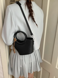Chic black lychee leather bucket bag with unique round handle shown on a model