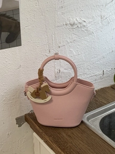 Pink lychee grain leather bucket bag with circular handle and rocking horse charm