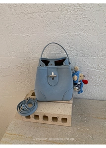 Detail of light blue bucket bag with leather texture, metal twist lock and cute bear charm