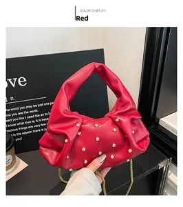 Close-up of red pleated dumpling bag with golden rhinestone studs and chain strap