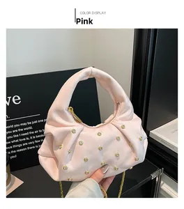 Detail of pink pleated dumpling bag featuring gold rivets and elegant chain strap