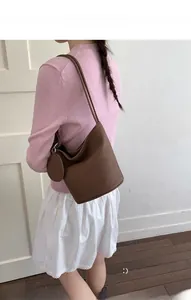 Brown leather bucket bag detail with a round matching coin purse accessory on the side