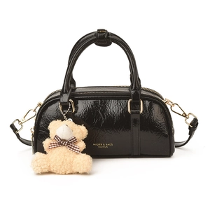 Sac à main chic en cuir verni noir avec détails dorés et pendentif ours en peluche