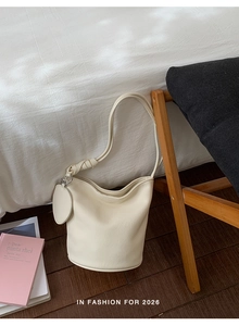 Close-up of beige bucket bag showing knotted handle detail and silver metal hardware