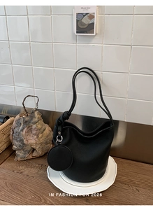 Detail of minimalist black pebbled leather bucket bag with matching round coin purse charm