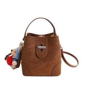 Vintage brown bucket bag with metallic twist lock, handle, and cute plush bear charm