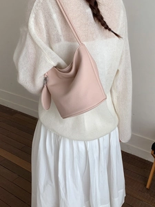 Minimalist light pink bucket bag with round coin purse on a shoulder strap shown on model