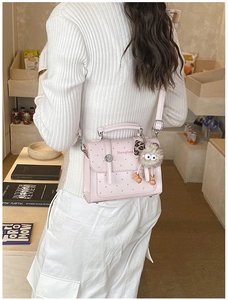 Pink polka dot PU leather handbag featuring a cute monster plush charm on shoulder strap