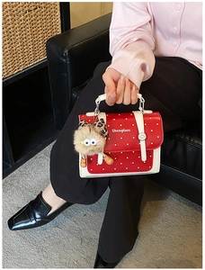 Detail of red and white polka dot handbag with plush eye charm and silver hardware