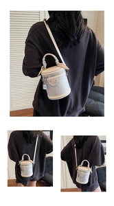 Détail du sac seau crème avec imprimé monogramme, anse foulard et breloque cadenas