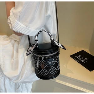 Détail d'un sac seau en cuir noir avec motifs géométriques et poignée en foulard de soie