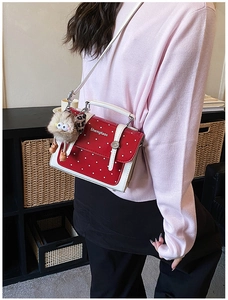 Detail view of red polka dot handbag with contrast white strap and cute plush charm