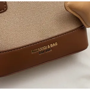 Détail de la texture du tissu et des coutures en cuir avec logo MIKAXIQI sur le sac