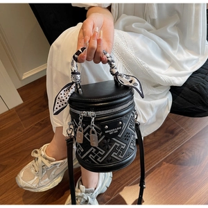Détail du sac seau cylindrique noir avec broderie géométrique et foulard en soie sur la poignée