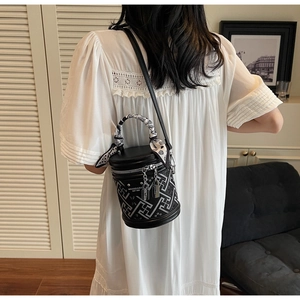 Détail d'un sac seau noir et blanc avec poignée en foulard décoratif et pendentif de cadenas